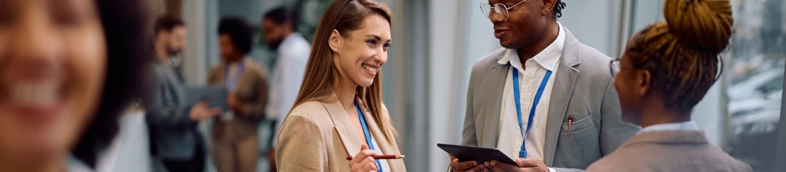 Conference attendees in discussion with one attendee holding a digital tablet